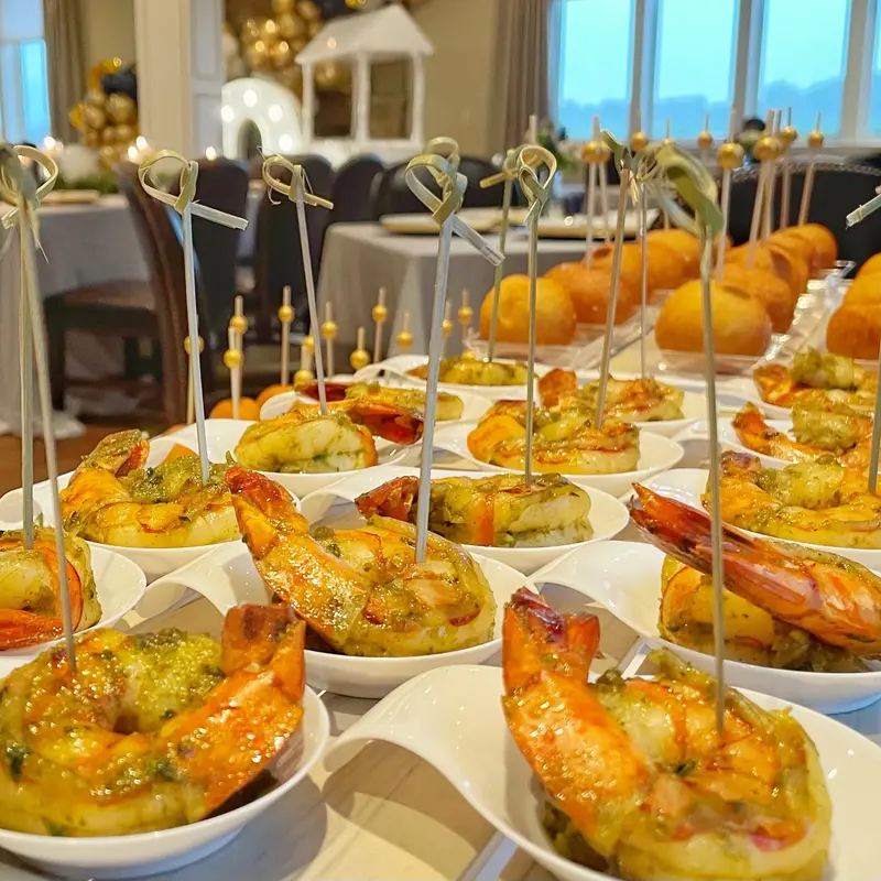 Herb-marinated shrimp cups lined up on a catered event table