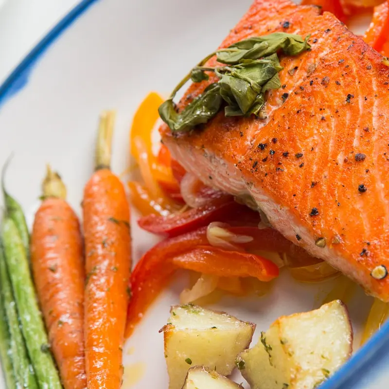 Close-up of crispy pan-roasted salmon with peppers and carrots