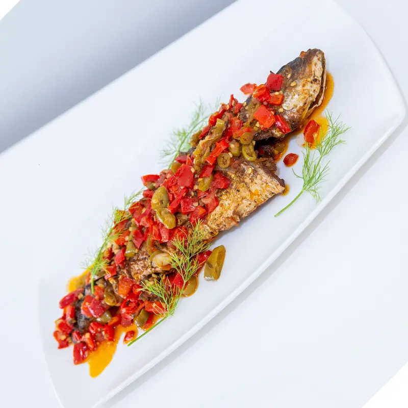 Roasted sea bass with pepper relish on a long white plate
